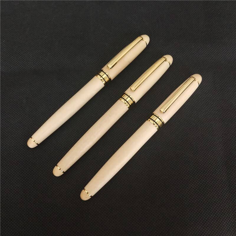 3 stylos à bille en bois sur un support noir